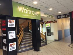 The Waitrose logo, over a flight of stairs.